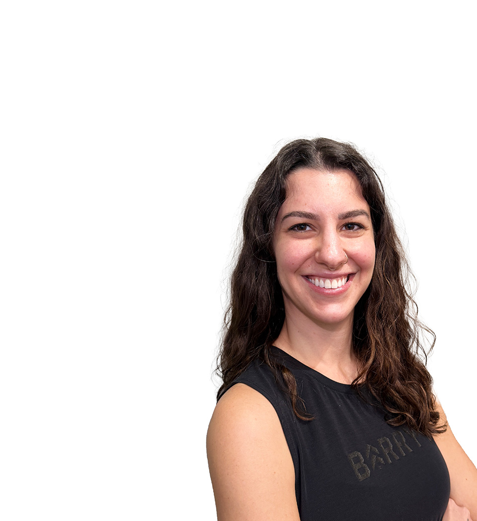 Barry’s instructor wearing a black top standing confidently smiling against a white background