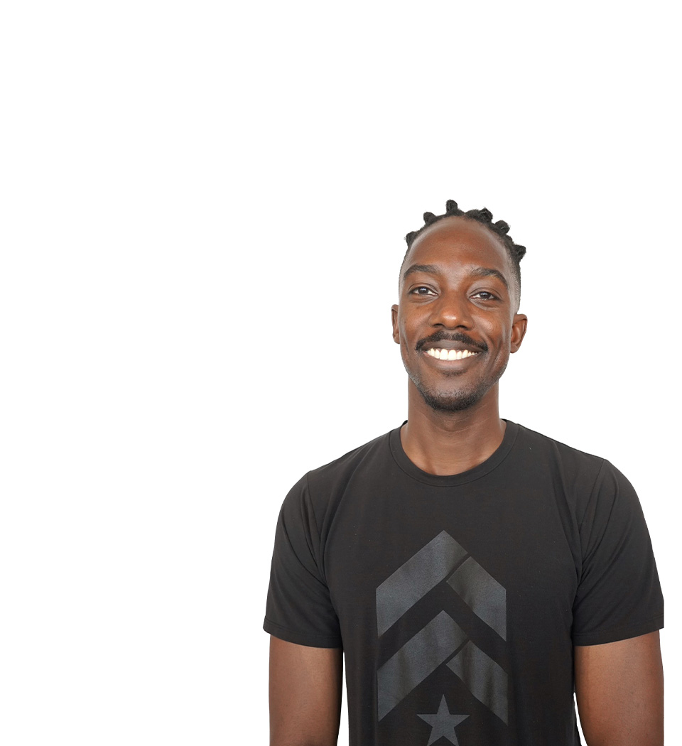 El instructor de Barry se mantiene firme, vistiendo una camiseta sin mangas negra sobre un fondo blanco, listo para el próximo desafío de entrenamiento.