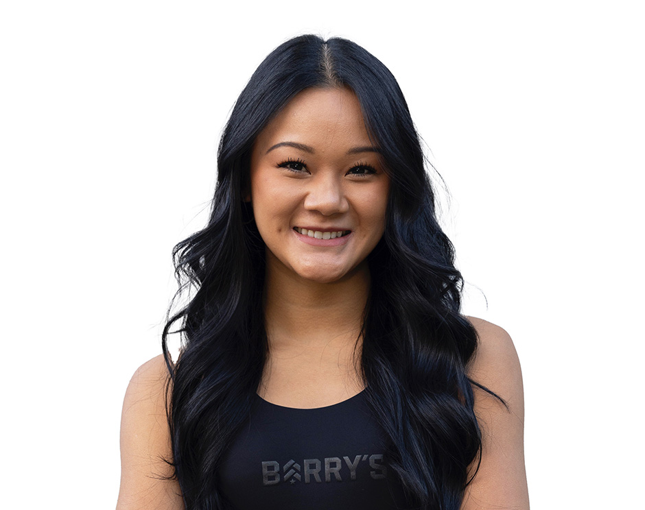 Barry’s instructor wearing a black top standing confidently smiling against a white background