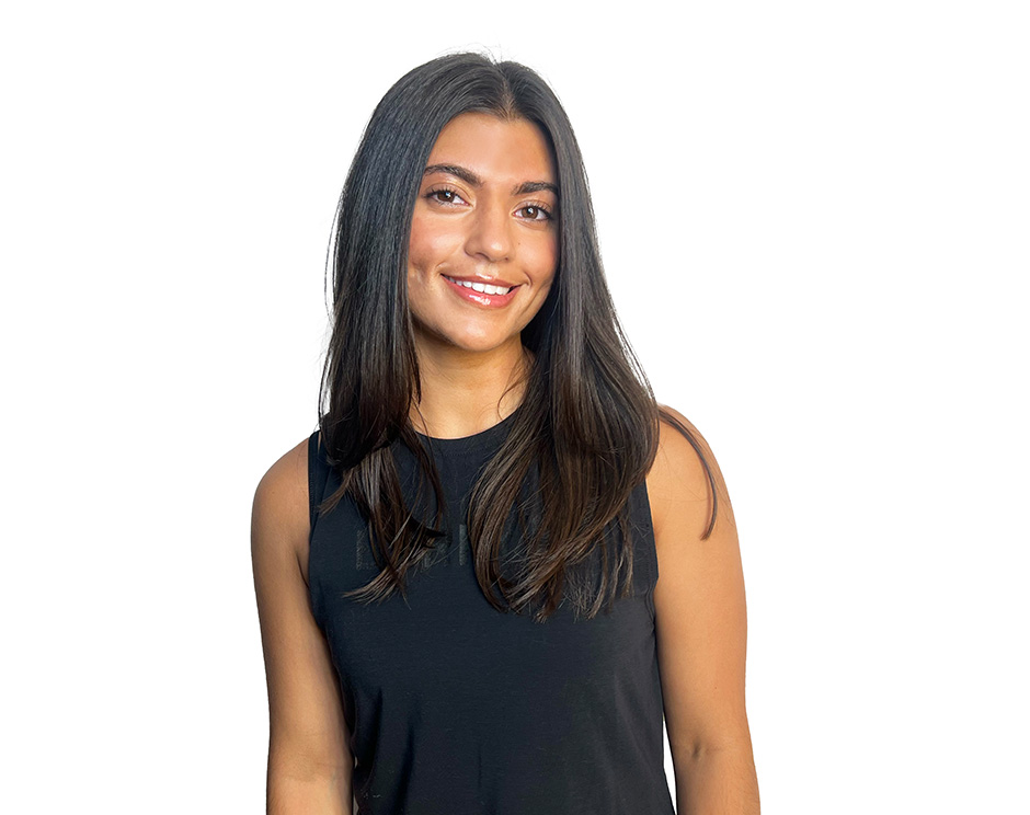 El instructor de Barry, con una camiseta negra, está de pie, sonriendo con confianza sobre un fondo blanco.