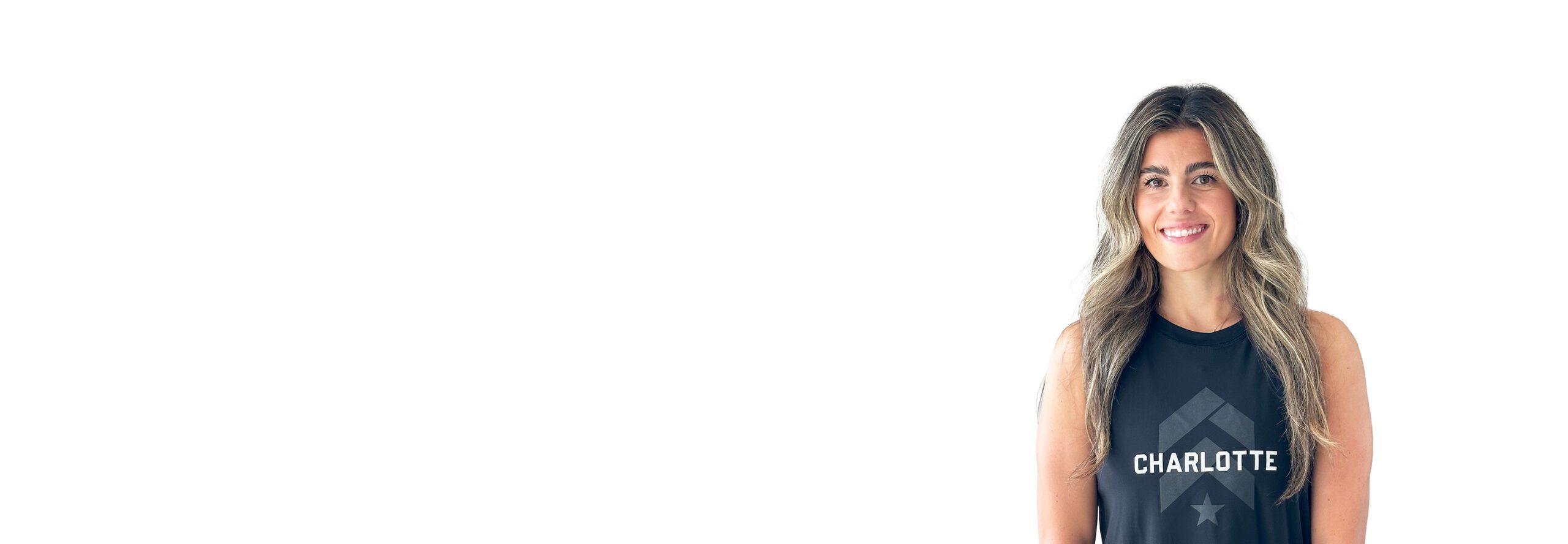 Barry’s instructor wearing a black top standing confidently smiling against a white background