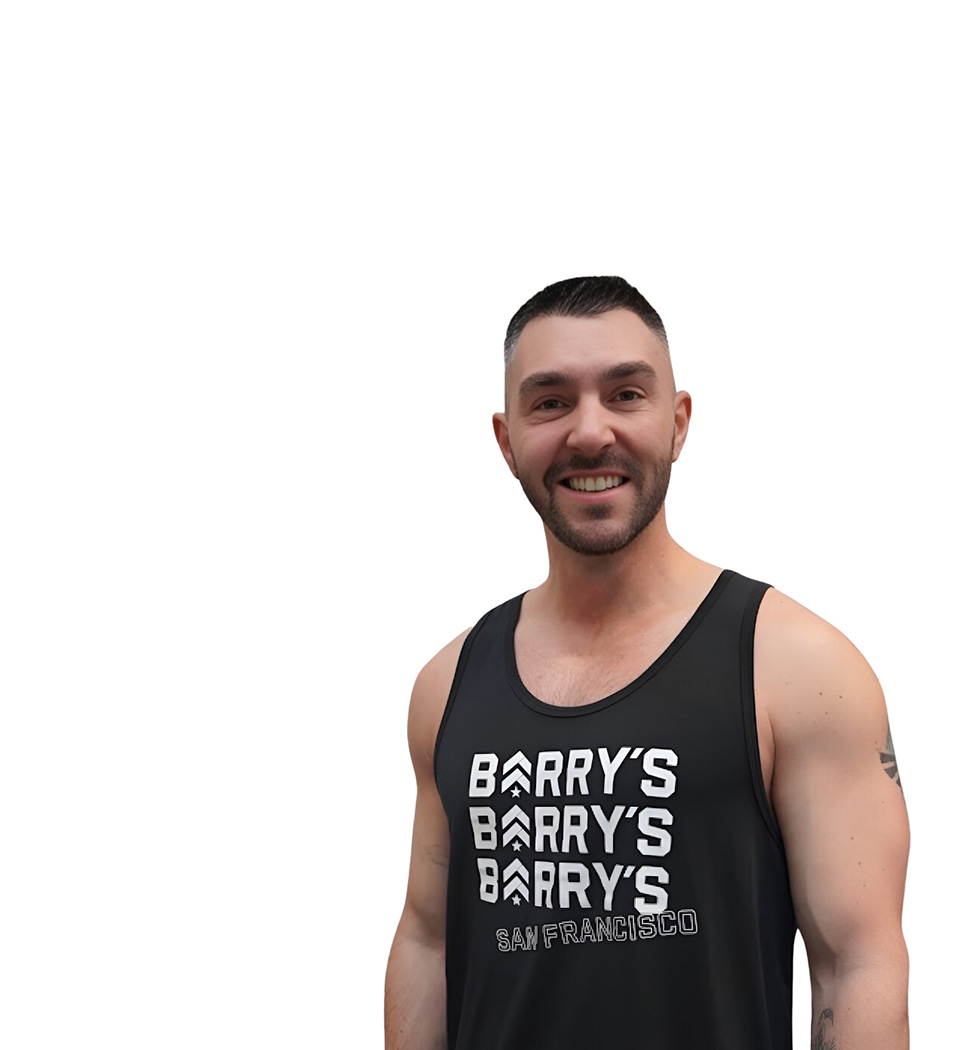 Barry’s instructor wearing a black top standing confidently smiling against a white background