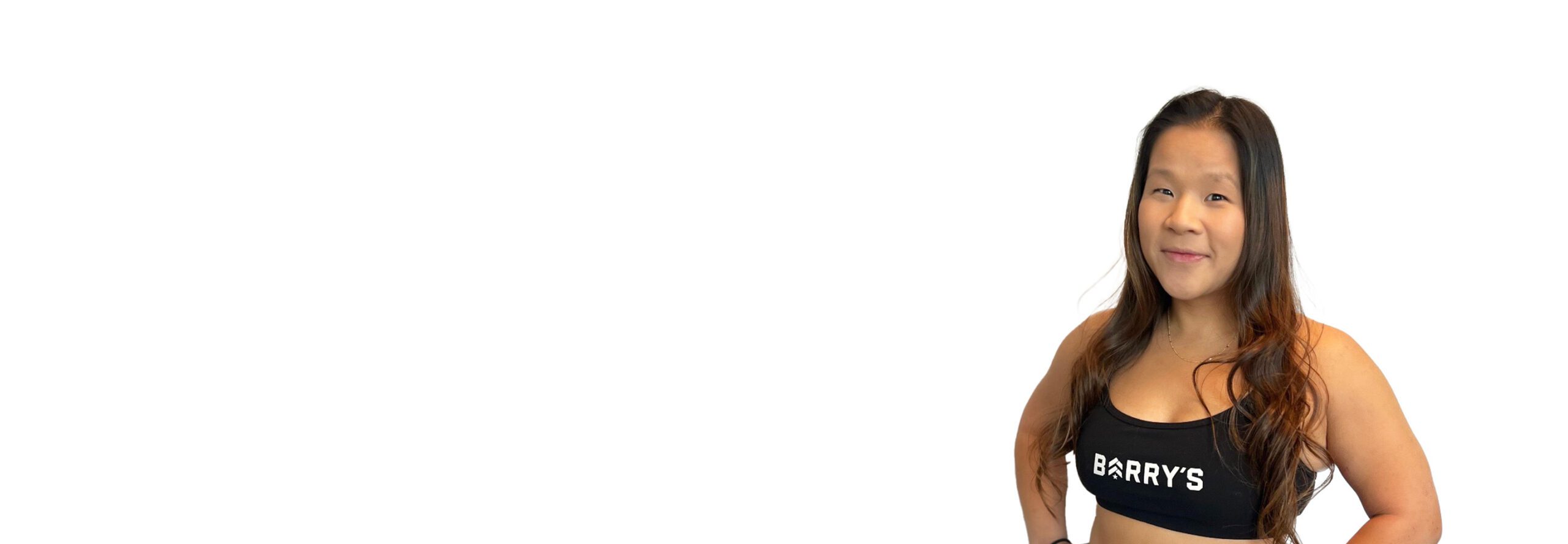 El instructor de Barry aparece de pie, con confianza, vistiendo una camiseta negra sobre un fondo blanco.