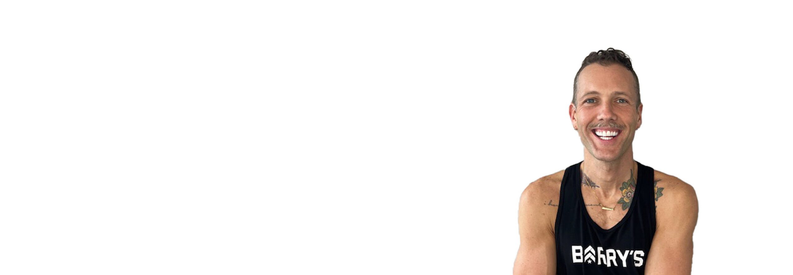 Barry’s instructor wearing a black top standing confidently smiling against a white background