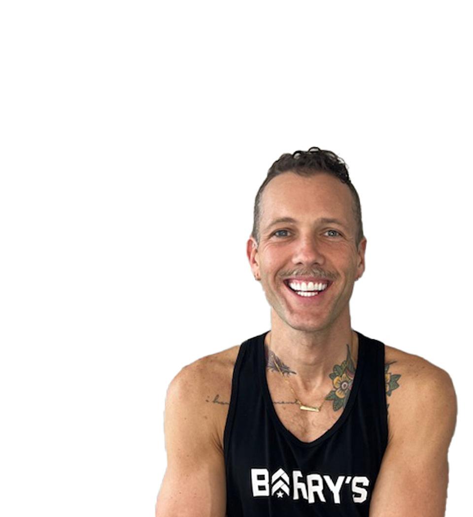Barry’s instructor wearing a black top standing confidently smiling against a white background