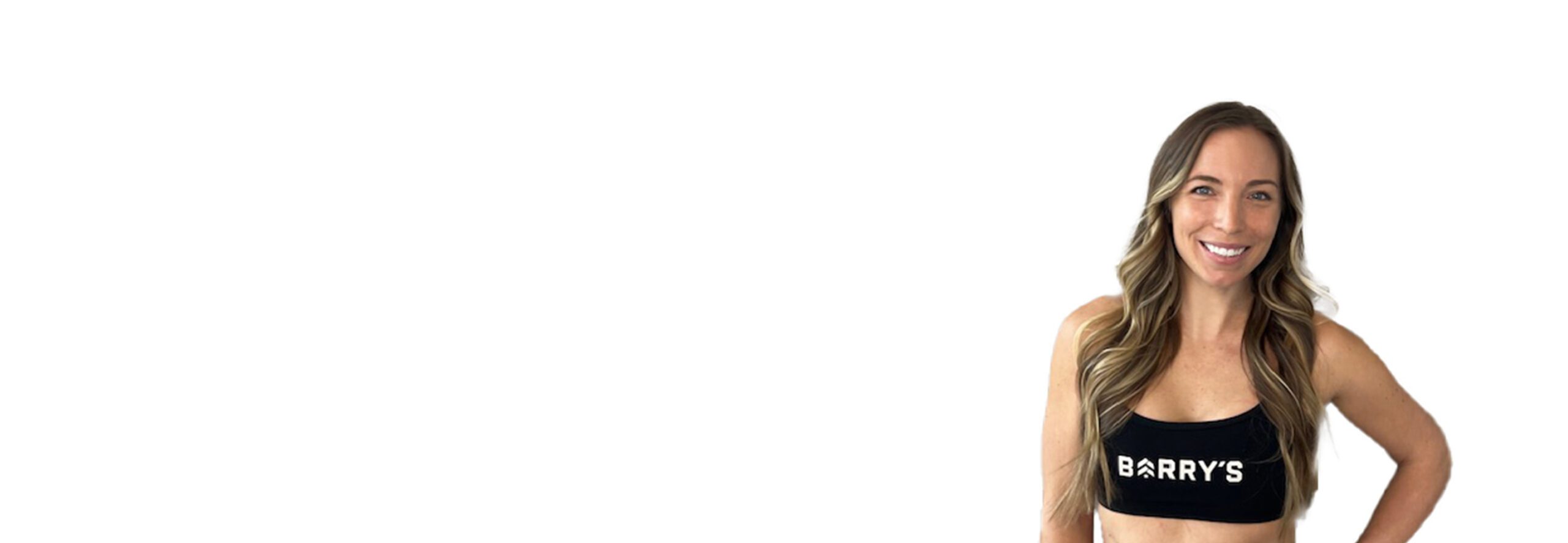Barry’s instructor wearing a black top standing confidently smiling against a white background