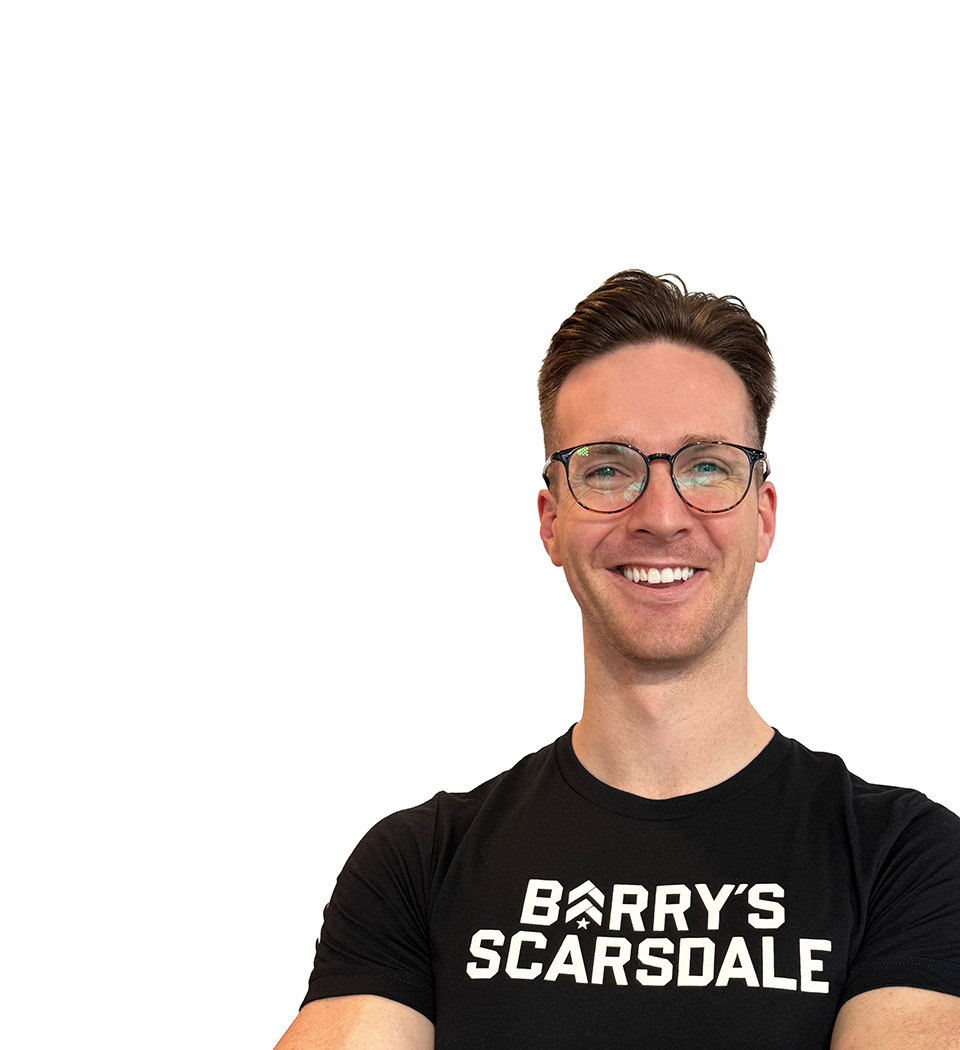 Barry’s instructor wearing a black top standing confidently smiling against a white background