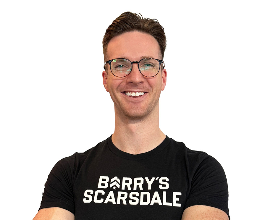 Barry’s instructor wearing a black top standing confidently smiling against a white background