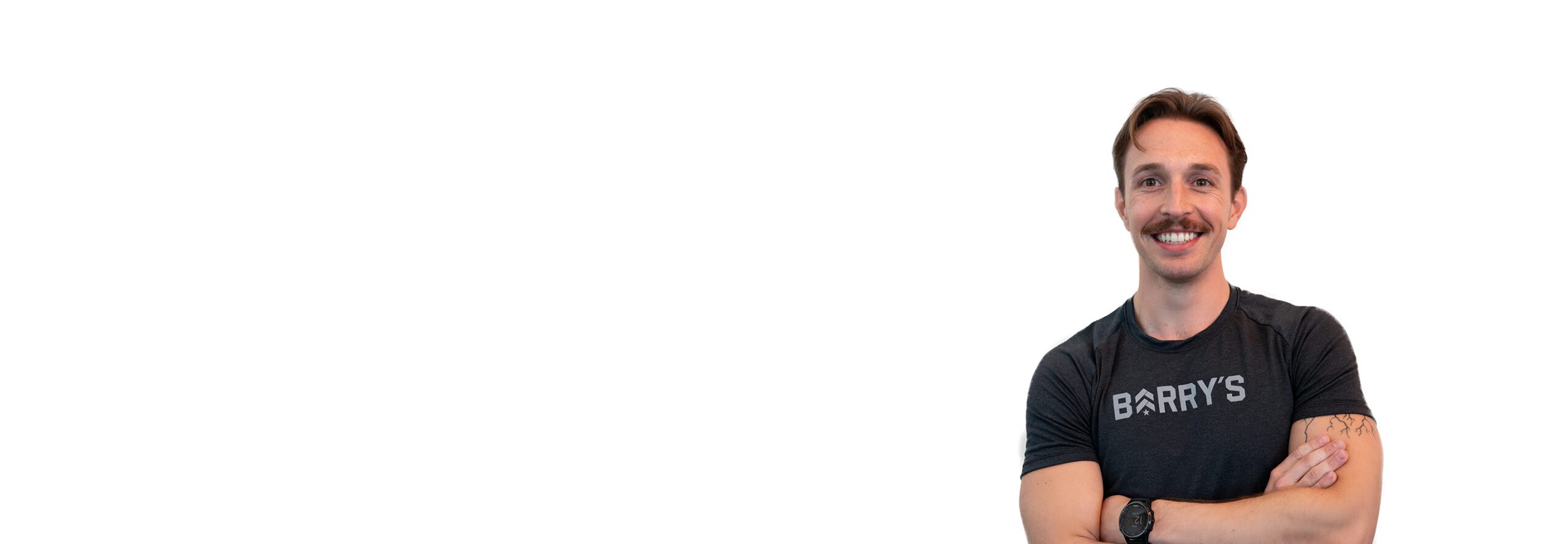 Barry’s instructor wearing a black top standing confidently smiling against a white background