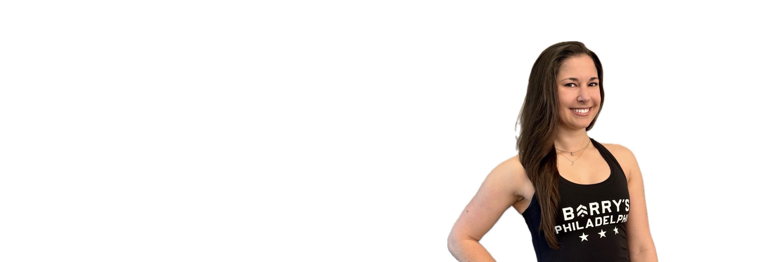 Barry’s instructor wearing a black top standing confidently smiling against a white background