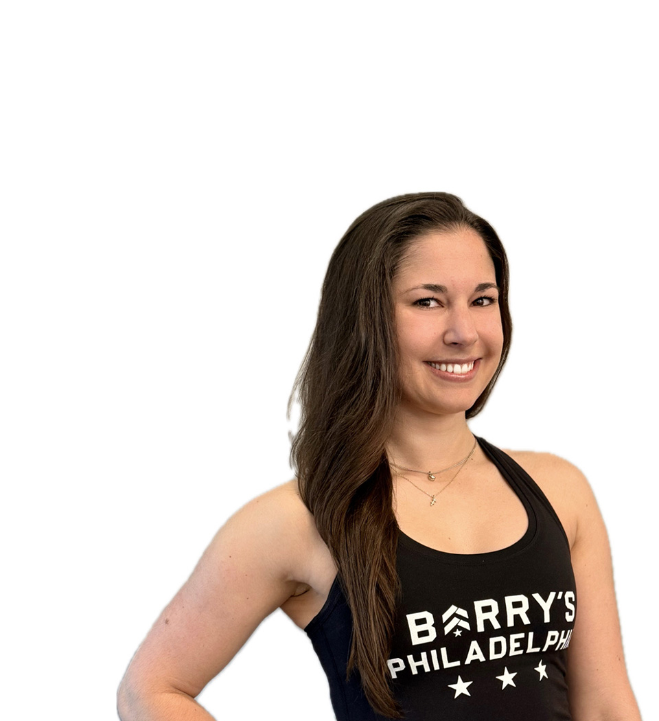 Barry’s instructor wearing a black top standing confidently smiling against a white background