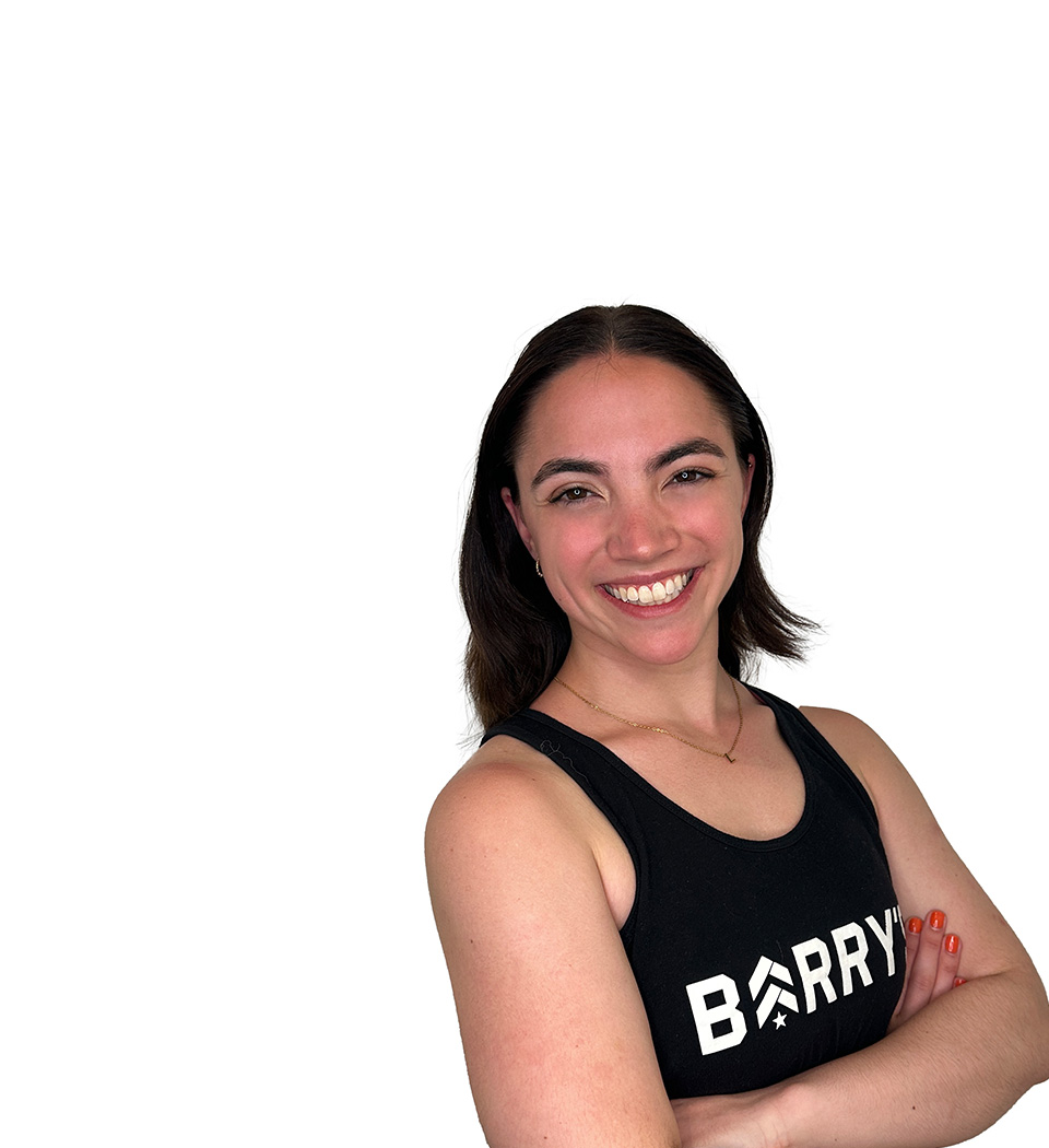 Barry’s instructor wearing a black top standing confidently smiling against a white background