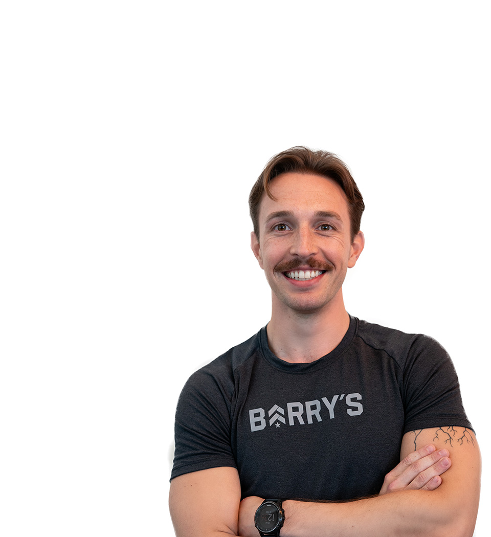 Barry’s instructor wearing a black top standing confidently smiling against a white background
