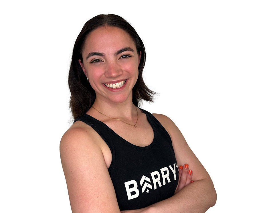Barry’s instructor wearing a black top standing confidently smiling against a white background