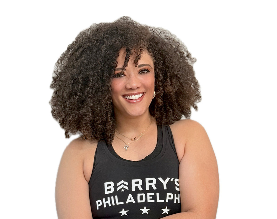 Barry’s instructor wearing a black top standing confidently smiling against a white background
