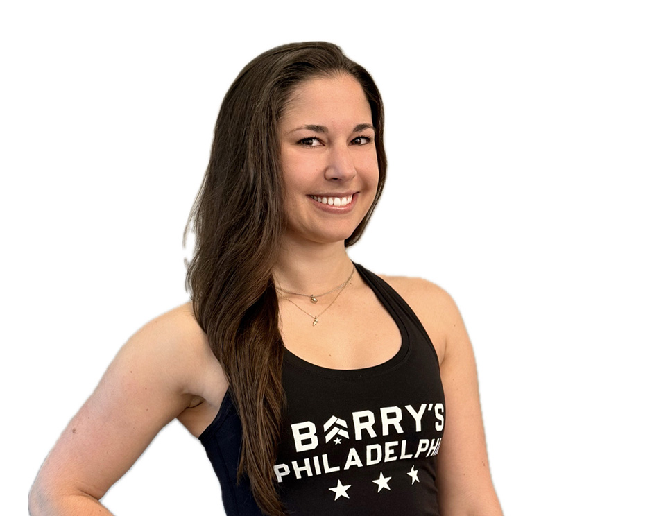Barry’s instructor wearing a black top standing confidently smiling against a white background