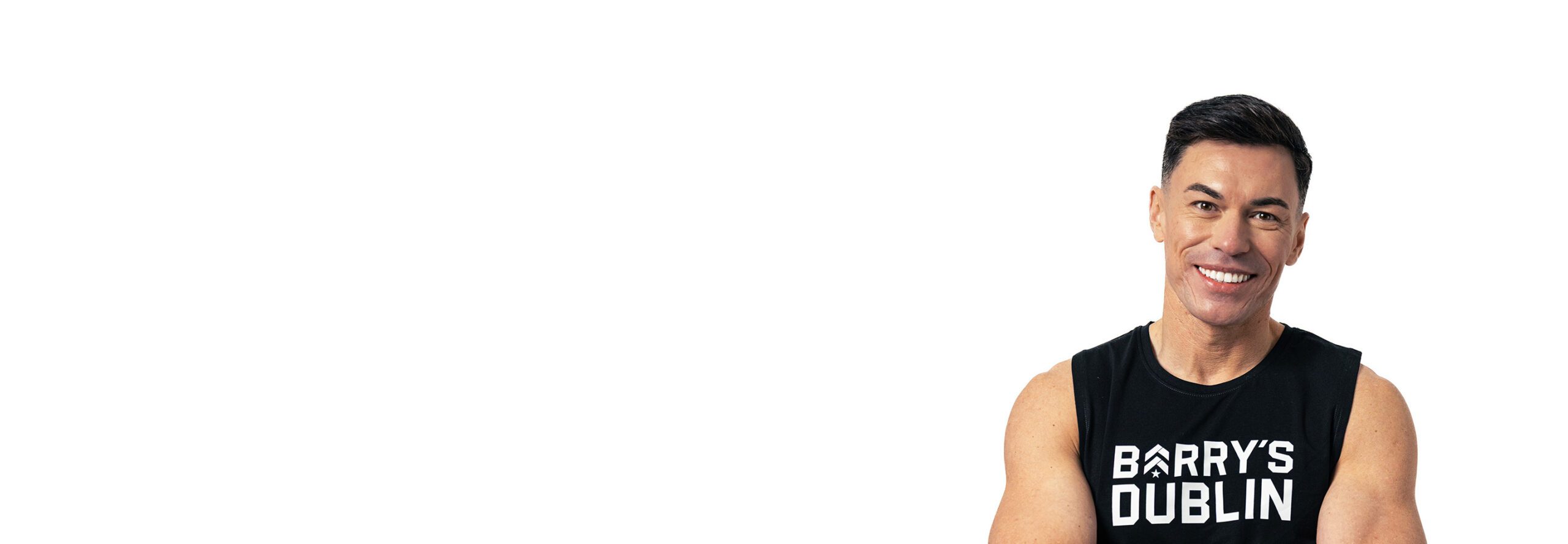 Barrys instruktör iklädd en svart topp står självsäkert och ler mot en vit bakgrund