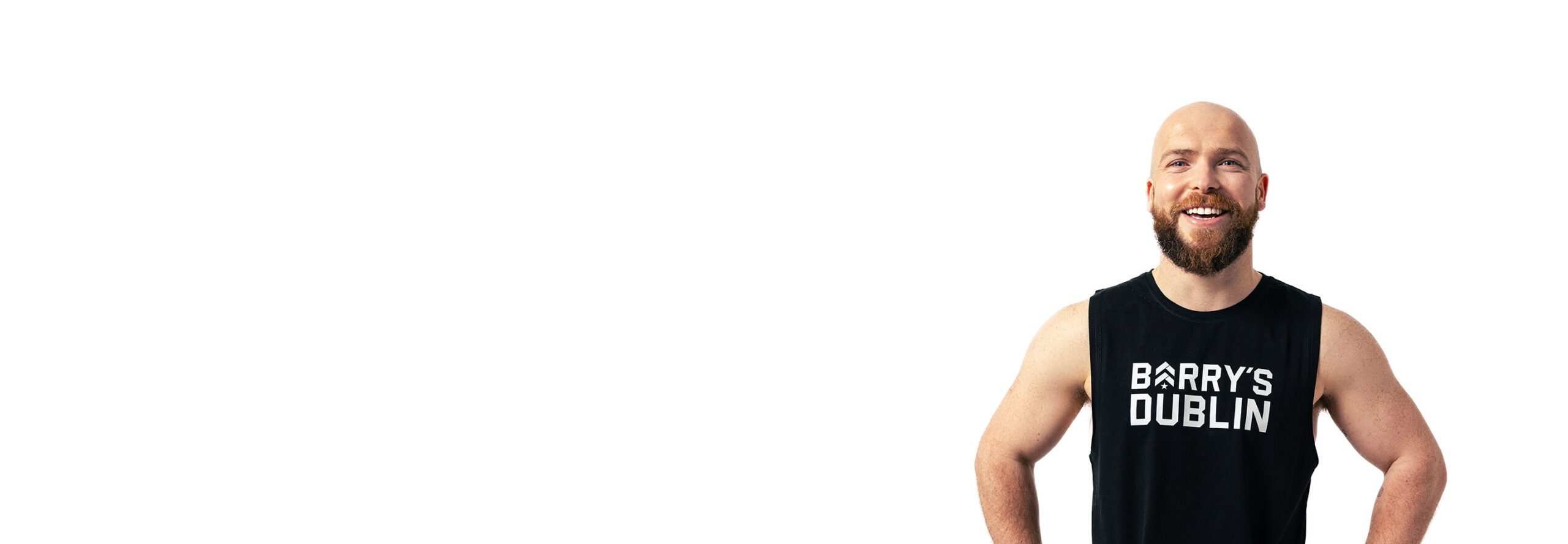 Barrys instruktör iklädd en svart topp står självsäkert och ler mot en vit bakgrund