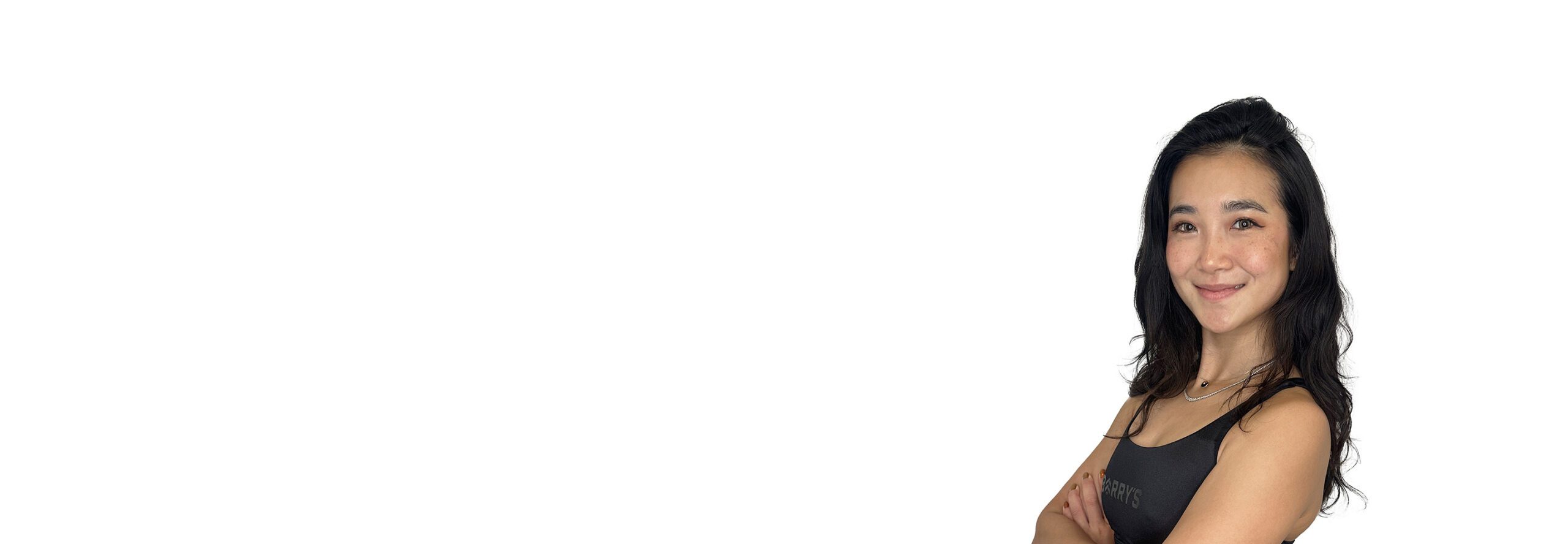 L'instructeur de Barry portant un haut noir se tient debout et sourit avec confiance sur un fond blanc