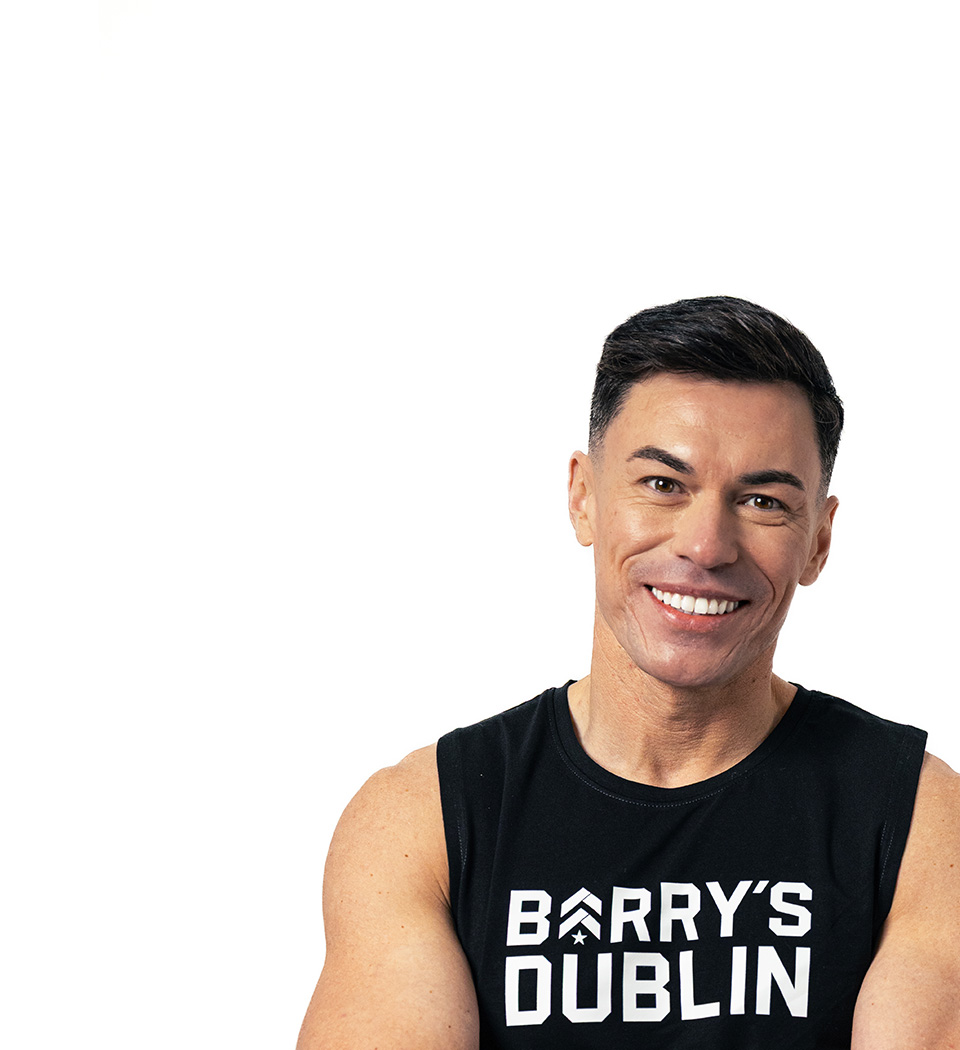 Barrys instruktör iklädd en svart topp står självsäkert och ler mot en vit bakgrund