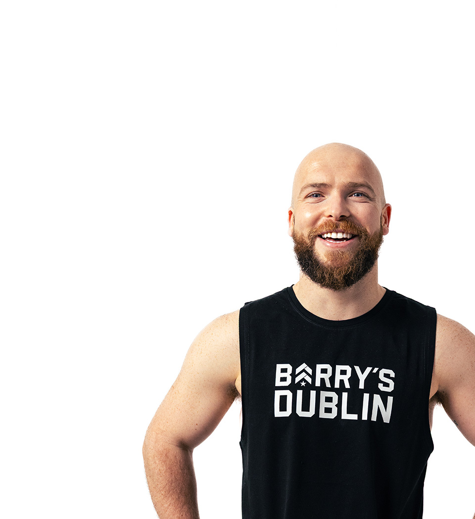 Barrys instruktör iklädd en svart topp står självsäkert och ler mot en vit bakgrund