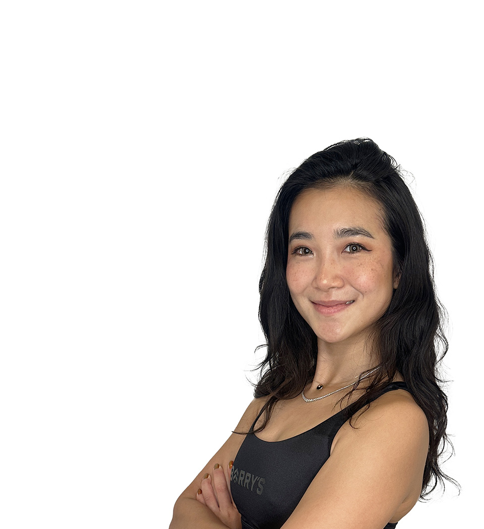 L'instructeur de Barry portant un haut noir se tient debout et sourit avec confiance sur un fond blanc