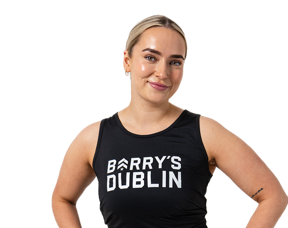 L'instructeur de Barry portant un haut noir se tient debout et sourit avec confiance sur un fond blanc