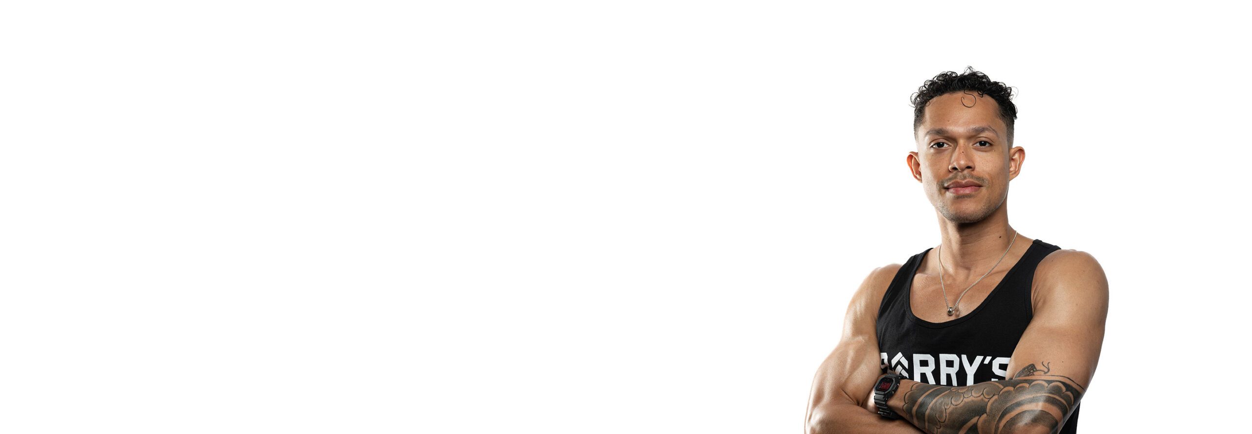 Barry’s instructor wearing a black top standing confidently smiling against a white background