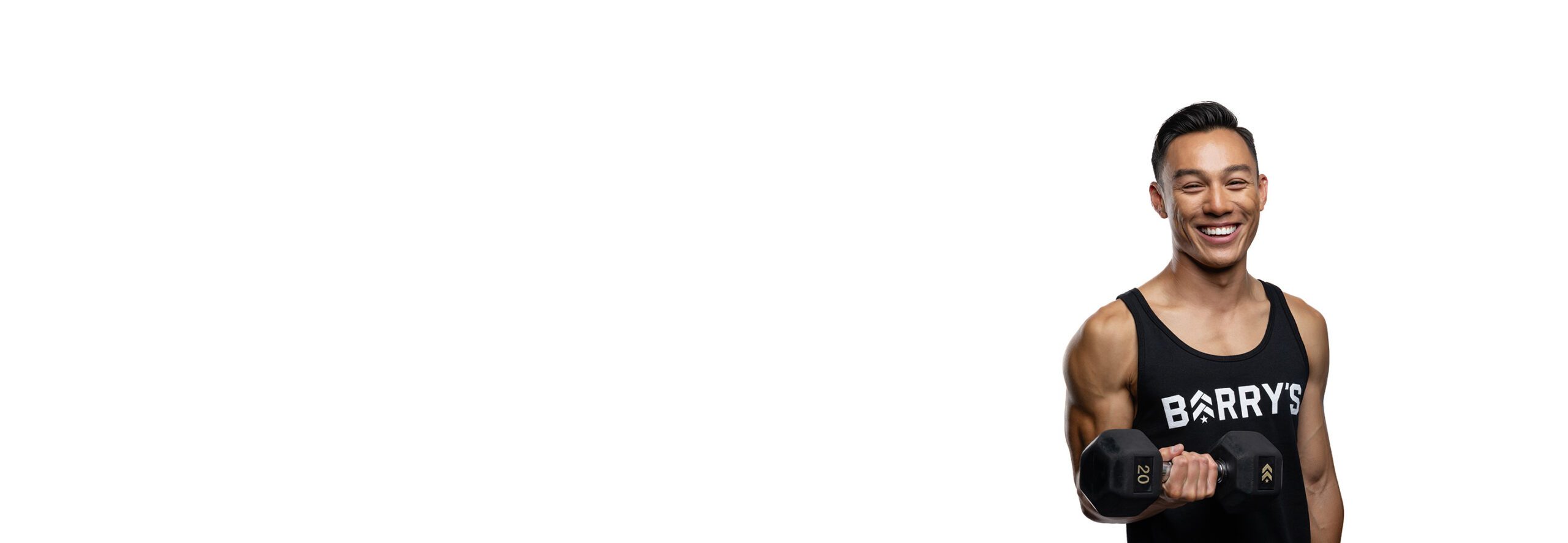 Barry’s instructor wearing a black top standing confidently smiling against a white background