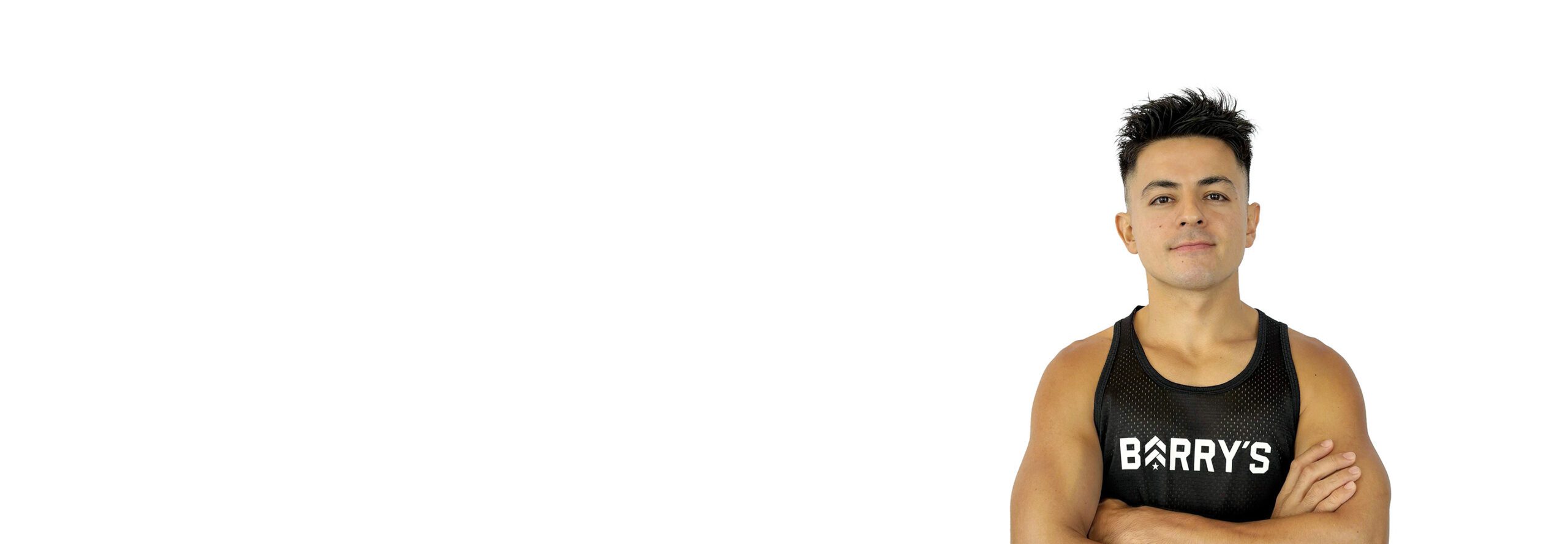 Barry’s instructor wearing a black top standing confidently smiling against a white background