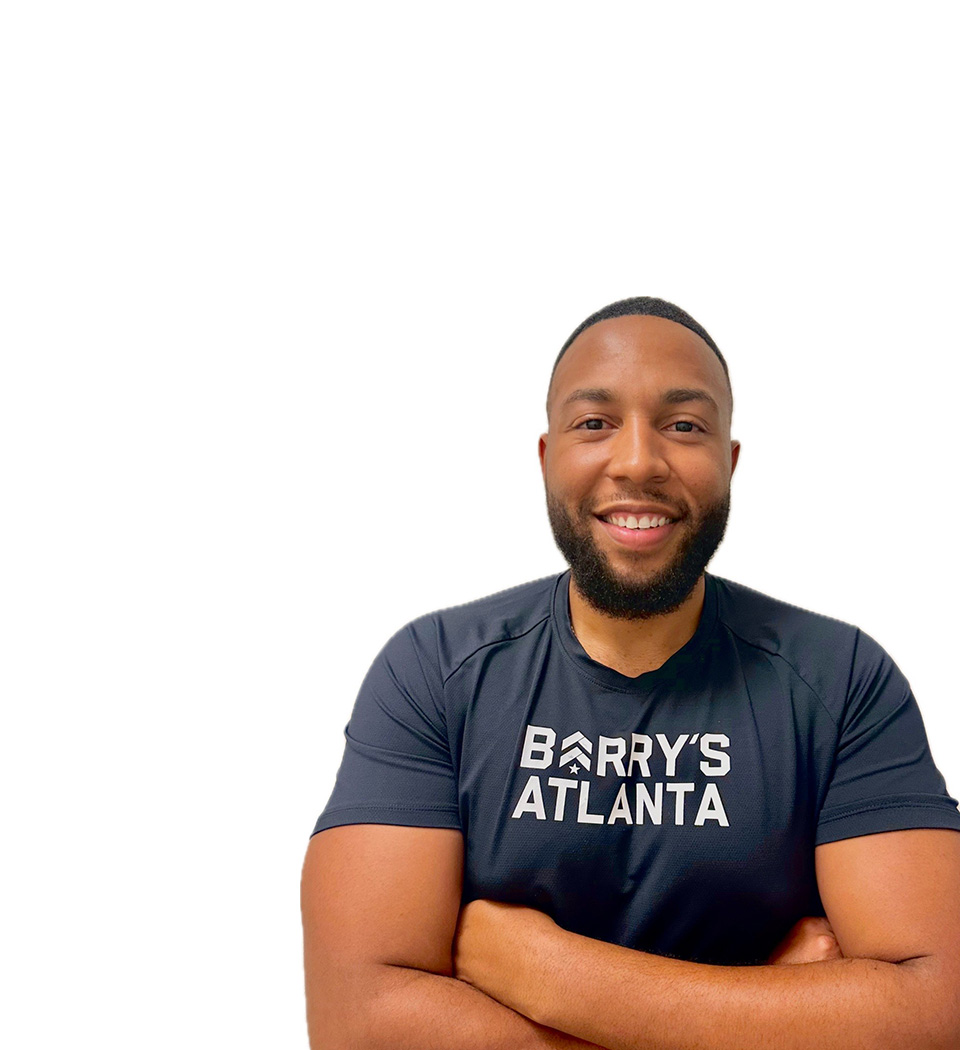 Barry’s instructor wearing a black top standing confidently smiling against a white background