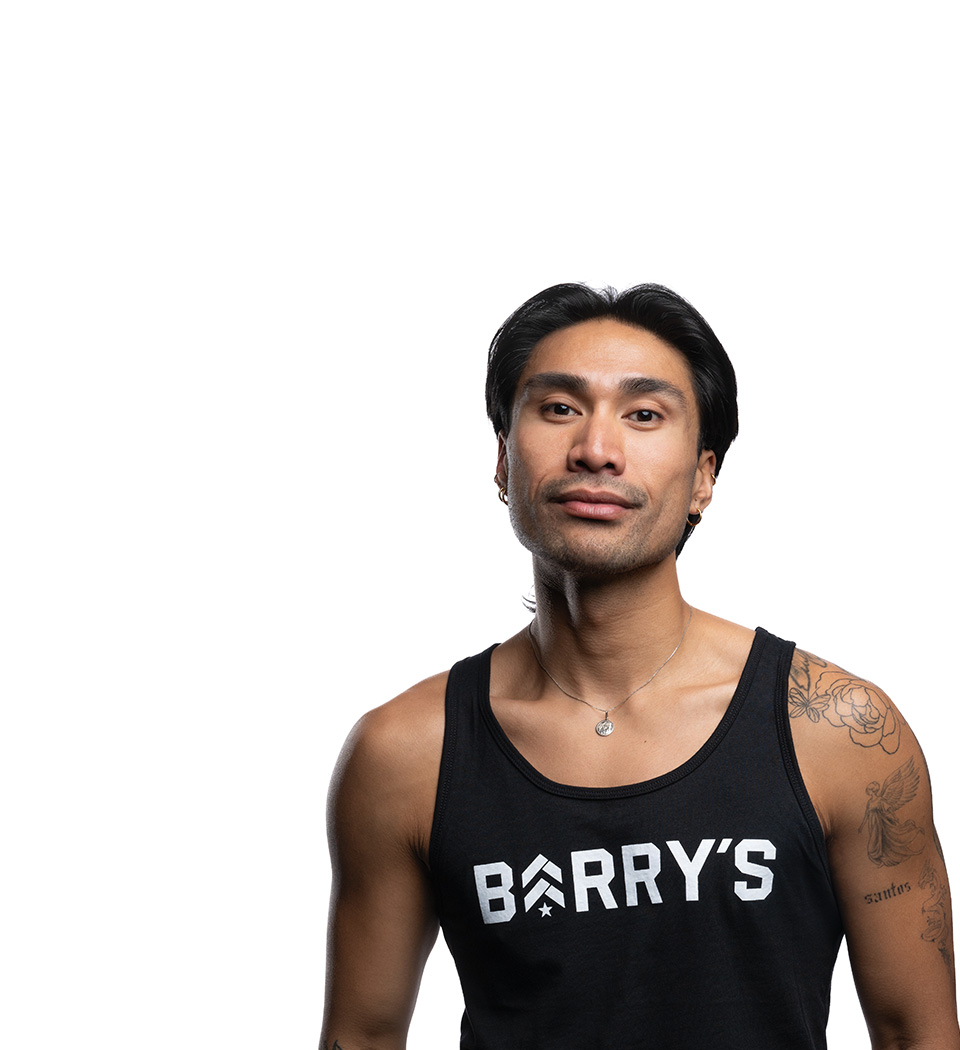 Barry’s instructor wearing a black top standing confidently smiling against a white background