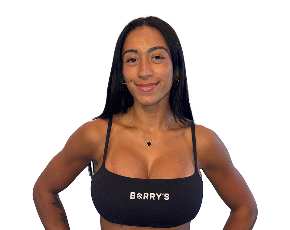 Barry’s instructor wearing a black top standing confidently smiling against a white background